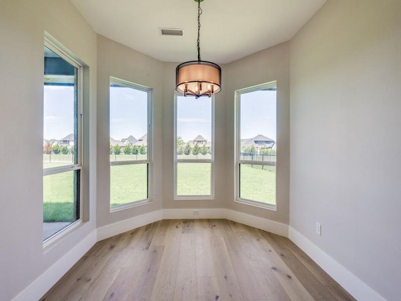 Breakfasts room dining area with a chandelier, light wood finished floors, and loving window to let in plenty of light