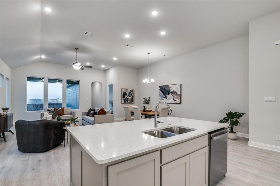 Kitchen featuring sink, a center island with sink, ceiling fan with notable chandelier, and light hardwood / wood-style flooring