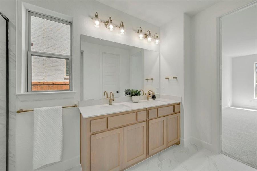Double vanity with light wood-finish cabinetry and white countertops