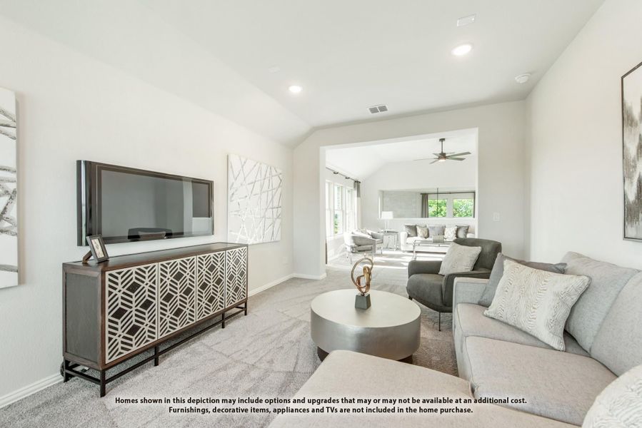 Living room with gray sofa, large TV on decorative console, and open view into sunlit family room with ceiling fan Living room with gray sofa, large TV on decorative console, and open view into sunlit family room with ceiling fan