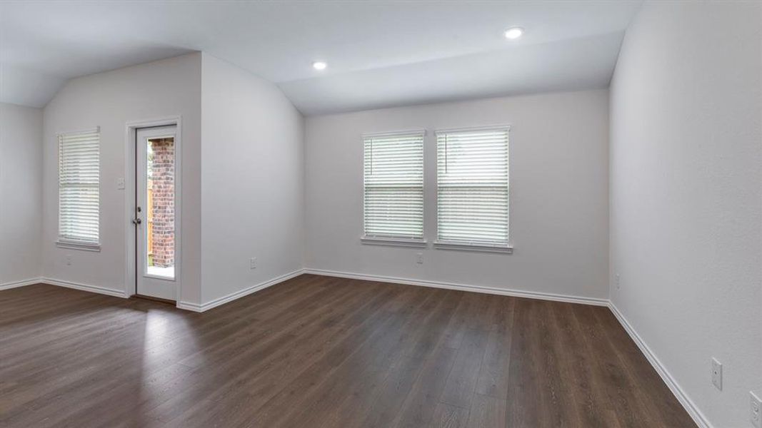 Empty room featuring vaulted ceiling, dark wood-style flooring, and recessed lighting