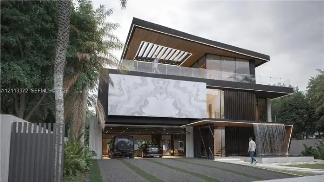 Contemporary multi-level exterior featuring a stone-clad facade, a covered ground-level parking area, a glass-railed upper terrace with a wood-paneled ceiling, and a built-in water feature