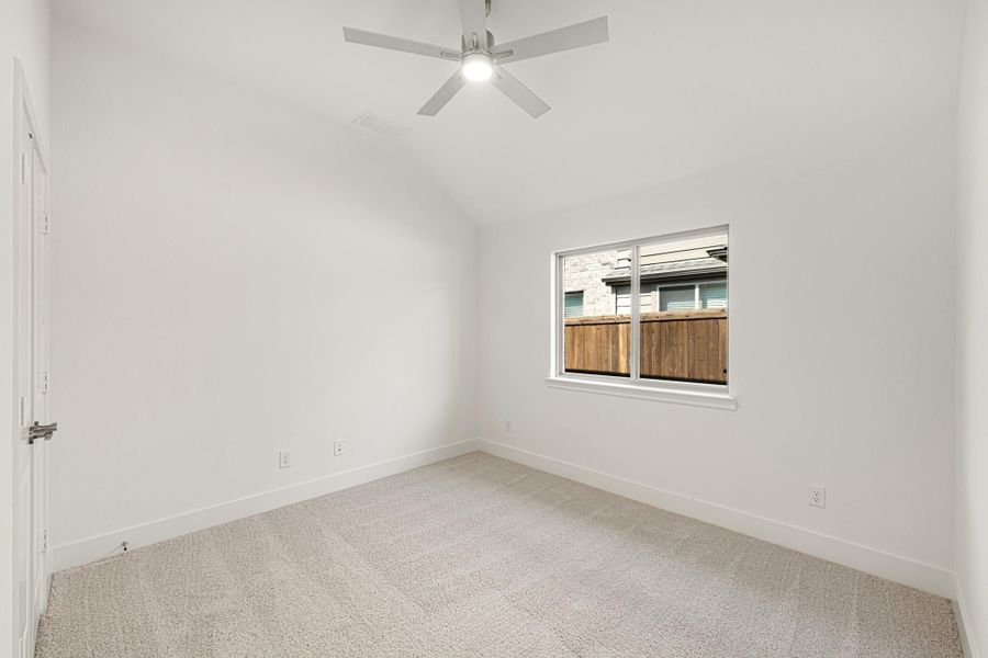 Empty bedroom with white walls, carpet flooring, ceiling fan, and single window with outdoor view