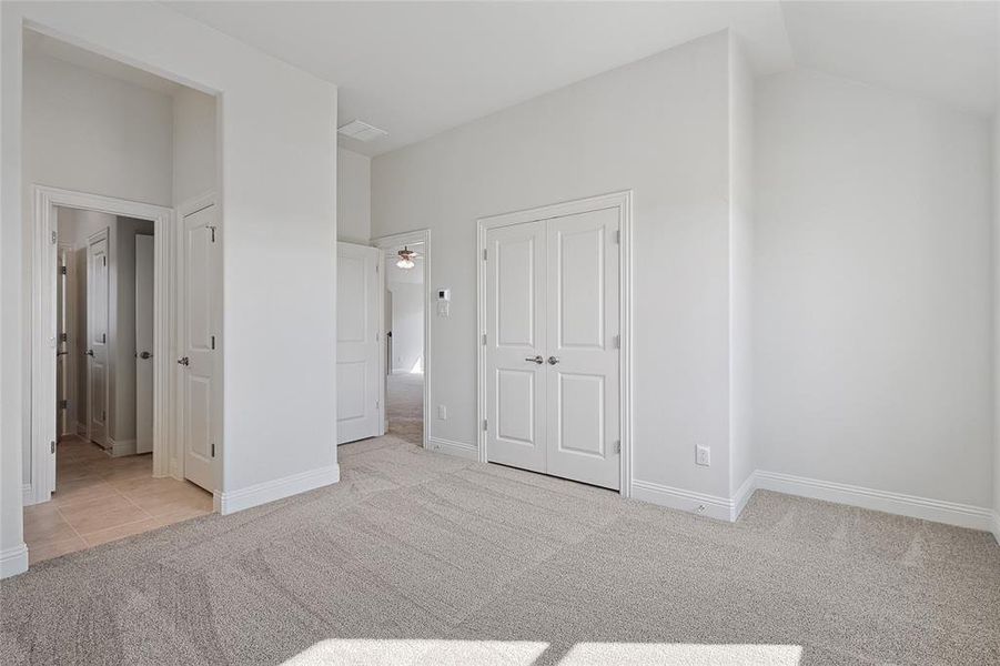 Unfurnished bedroom with light carpet, a closet, and lofted ceiling Unfurnished bedroom with light carpet, a closet, and lofted ceiling