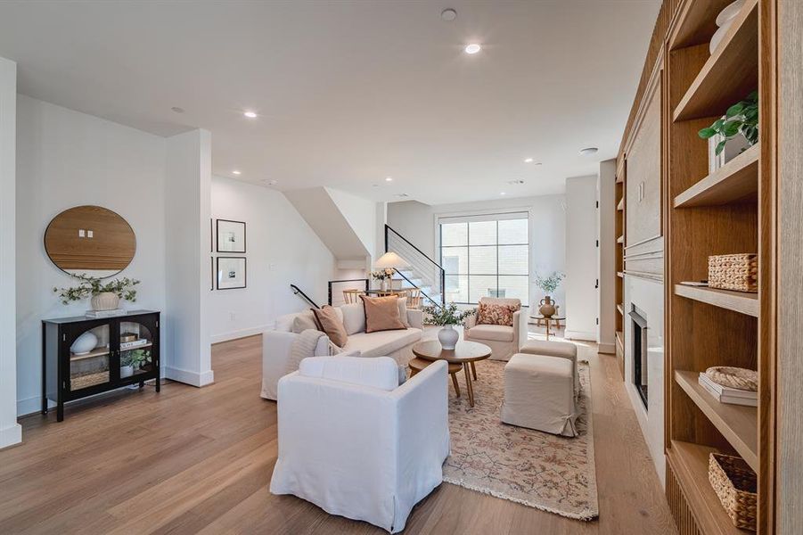 Living room with light wood-style flooring, a fireplace, recessed lighting, and stairway