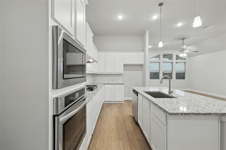 Kitchen featuring light wood-style flooring, stainless steel appliances, a ceiling fan, white cabinets, and recessed lighting Kitchen featuring light wood-style flooring, stainless steel appliances, a ceiling fan, white cabinets, and recessed lighting