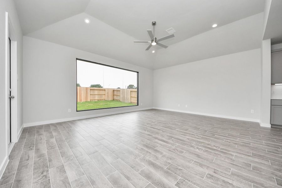Welcome family and guests to your charming living room! With its high ceilings, recessed lighting, ceiling fan, custom paint, beautiful flooring, and large windows that let in abundant natural light, this room is perfect for gatherings. Sample photo of completed home with similar floor plan. Actual colors and selections may vary.