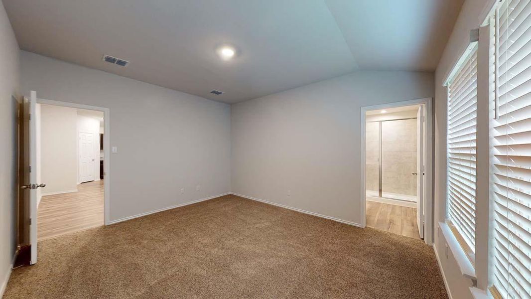 Spacious room featuring vaulted ceilings, recessed lighting, neutral wall paint, and brown carpet flooring