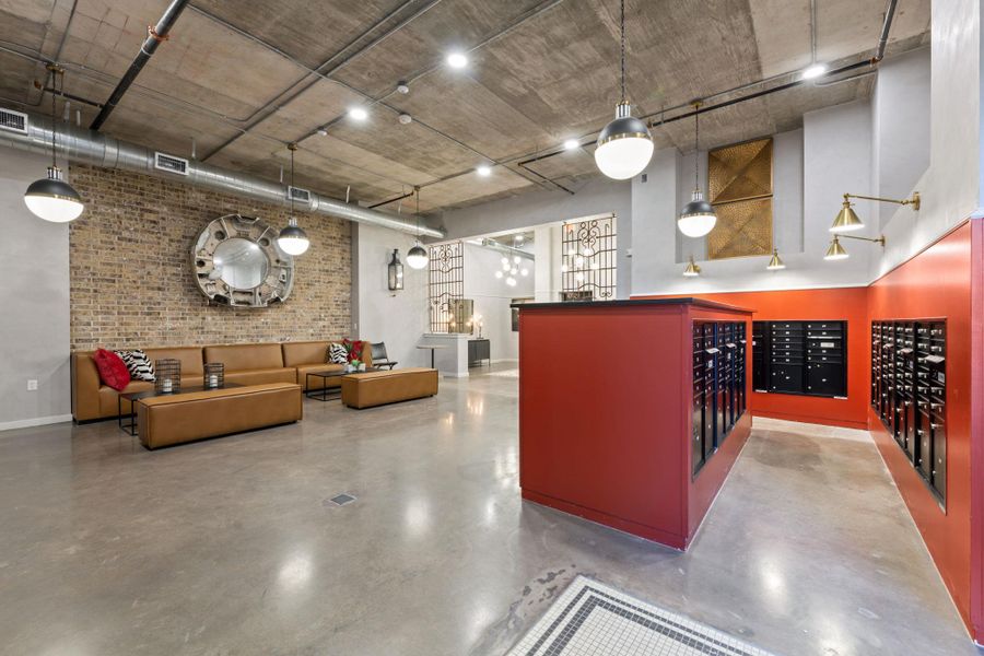 Reception area with mail area, a high ceiling, and brick wall