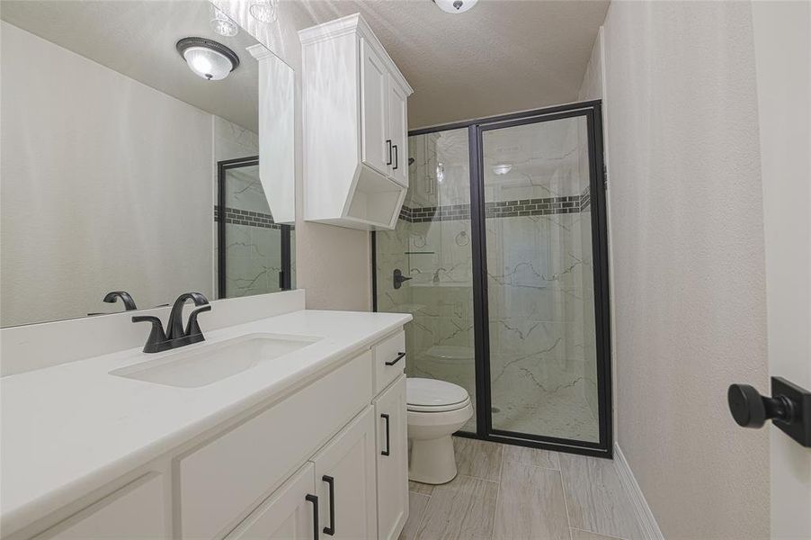 Bathroom featuring a marble finish shower and vanity