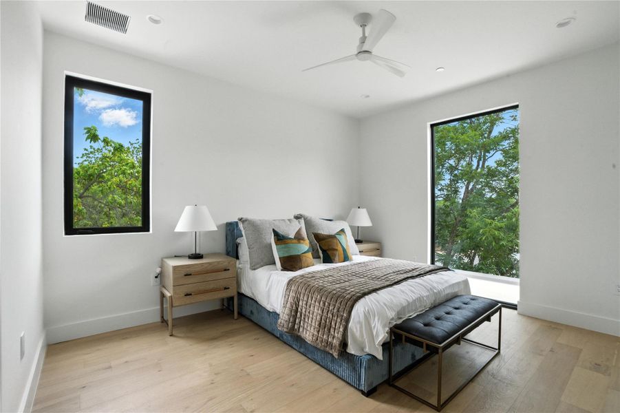 Bedroom with multiple windows, light wood finished floors, and a ceiling fan Bedroom with multiple windows, light wood finished floors, and a ceiling fan