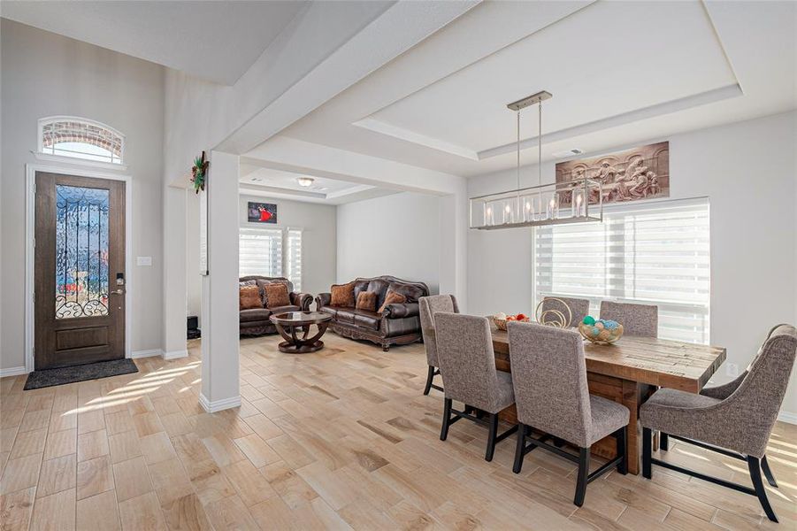 Dining space with a raised ceiling and light hardwood / wood-style floors