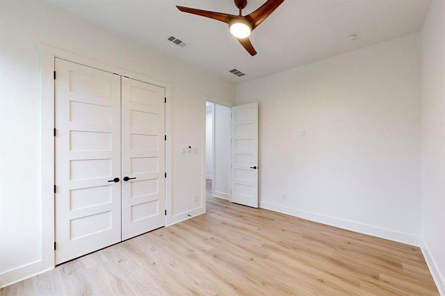 Spacious room featuring wood-finish flooring, crisp white walls, and a contemporary ceiling fan with integrated lighting Spacious room featuring wood-finish flooring, crisp white walls, and a contemporary ceiling fan with integrated lighting