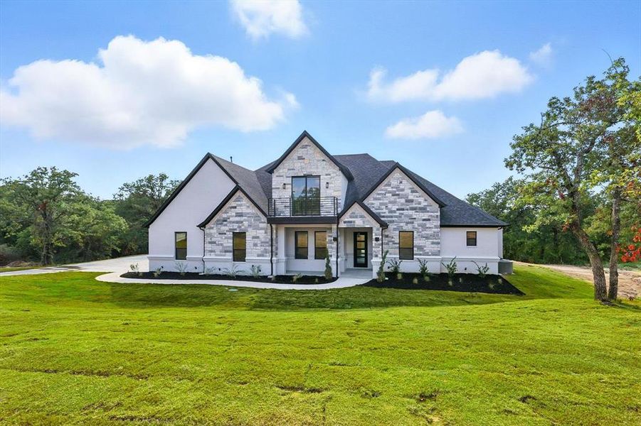 French country inspired facade featuring stone siding and a front lawn French country inspired facade featuring stone siding and a front lawn