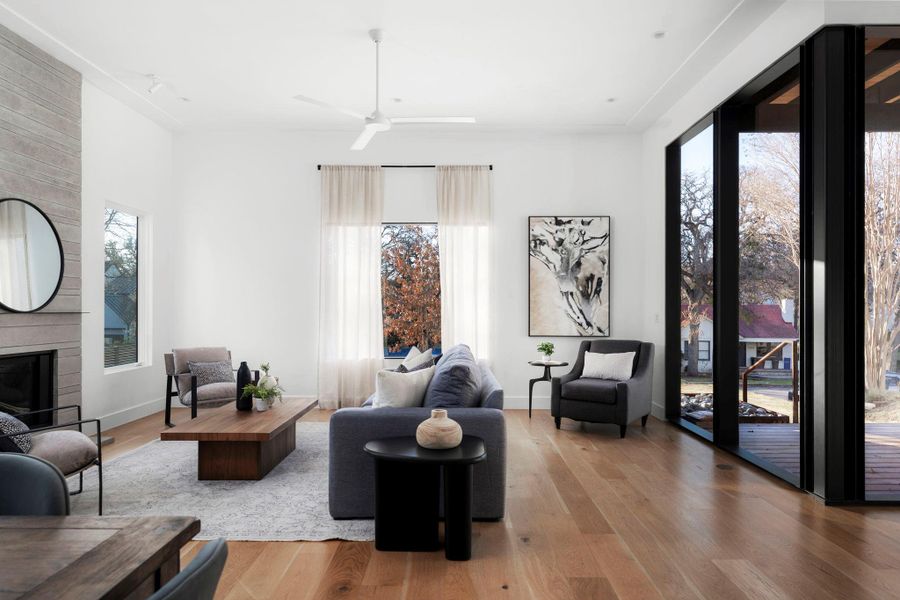 Living room featuring a brick fireplace, wood-type flooring, and a ceiling fan
