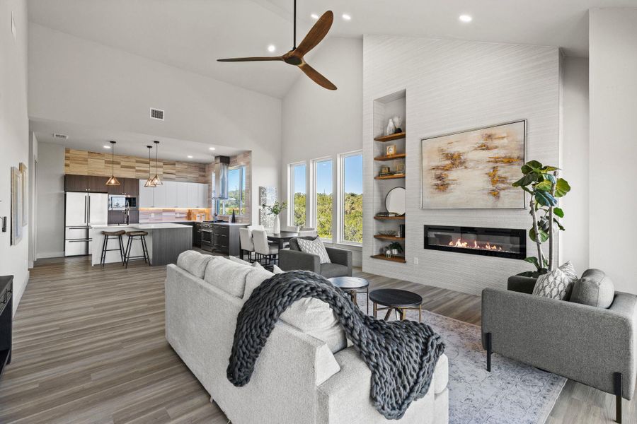 Living area with visible vents, wood finished floors, high vaulted ceiling, and a glass covered fireplace