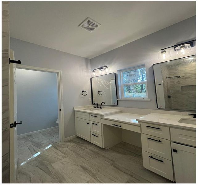 Bathroom featuring vanity, walk in shower, and toilet