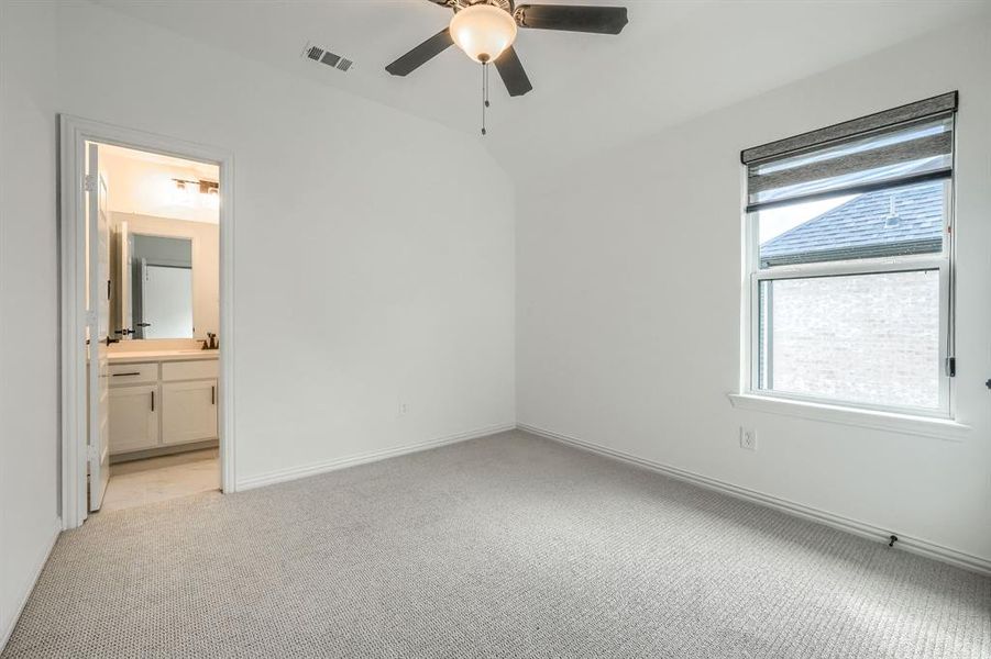 Unfurnished bedroom with visible vents, a ceiling fan, ensuite bath, baseboards, and light colored carpet