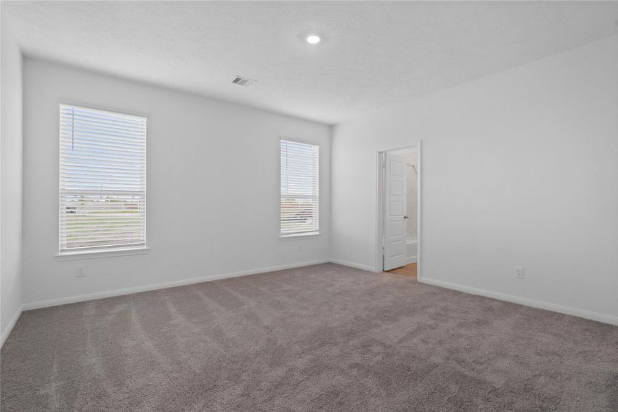 Relax and recharge in this stunning primary suite! Enjoy the comfort of plush carpeting, neutral-toned walls, high ceilings, recessed lighting, and large windows that fill the room with natural light.
