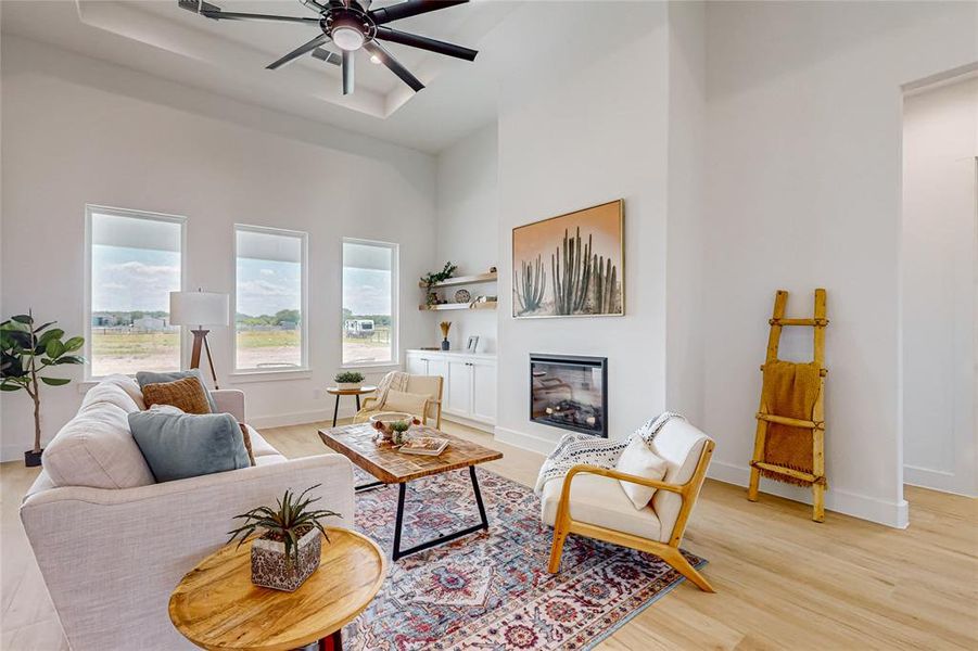 Living room featuring a towering ceiling, ceiling fan, and light hardwood / wood-style flooring