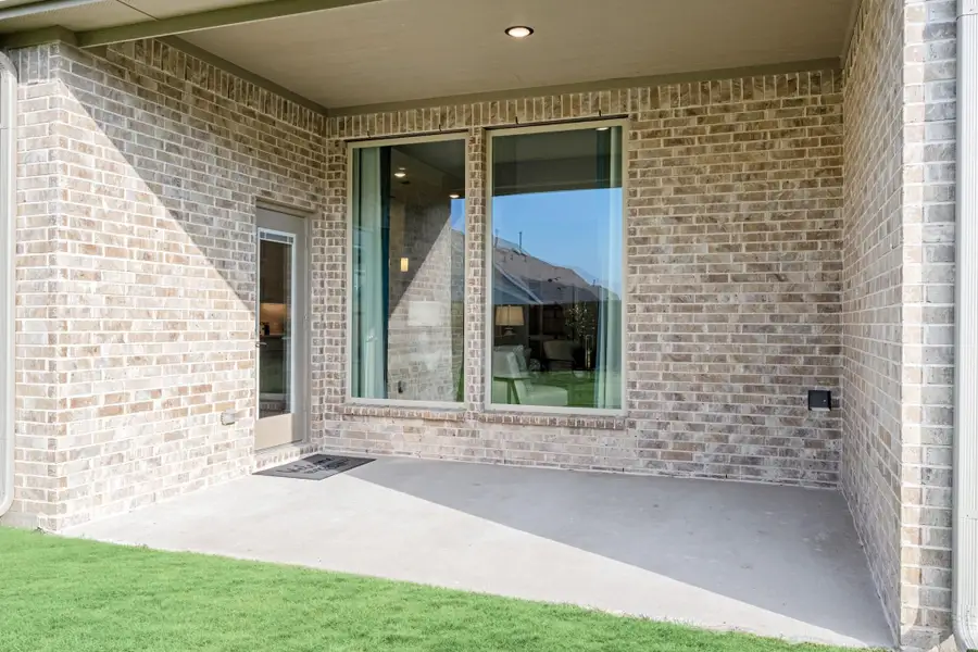 Covered back patio with concrete floor, brick exterior, large windows, and glass door leading inside Covered back patio with concrete floor, brick exterior, large windows, and glass door leading inside