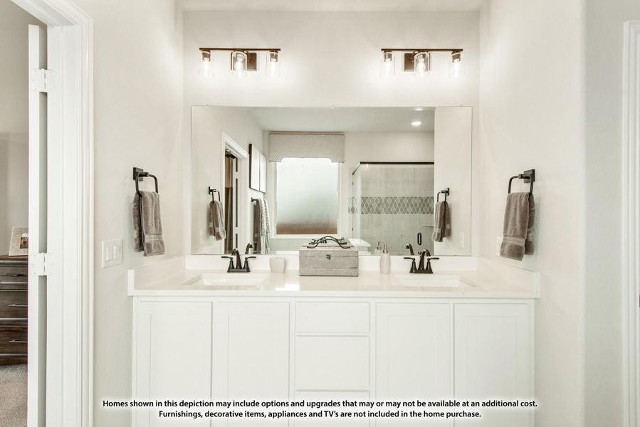 Bathroom with double sink vanity, white cabinets, large mirror, and glass shower in background