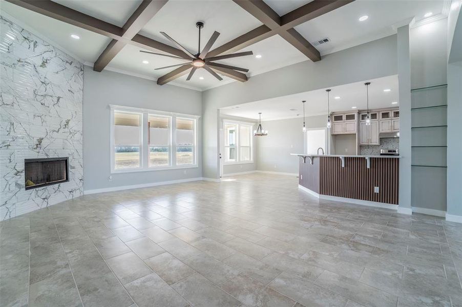 Unfurnished living room featuring a ceiling fan, a premium fireplace, coffered ceiling, a chandelier, and beam ceiling Unfurnished living room featuring a ceiling fan, a premium fireplace, coffered ceiling, a chandelier, and beam ceiling
