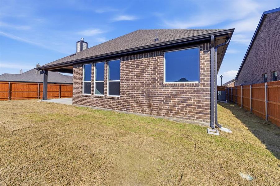 Back of house featuring a fenced backyard, brick siding, a patio, and a chimney