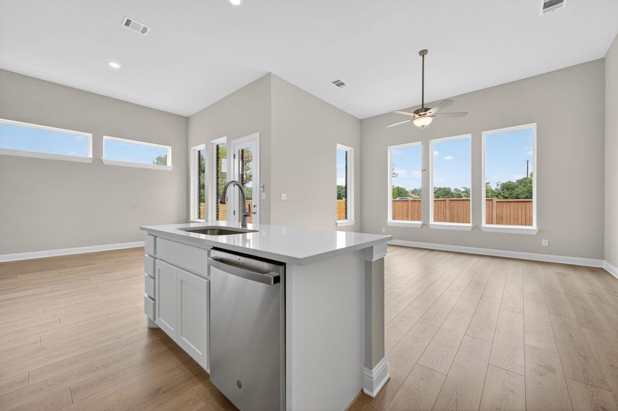 Kitchen with dishwasher, light wood-style flooring, a kitchen island with sink, open floor plan, and white cabinets