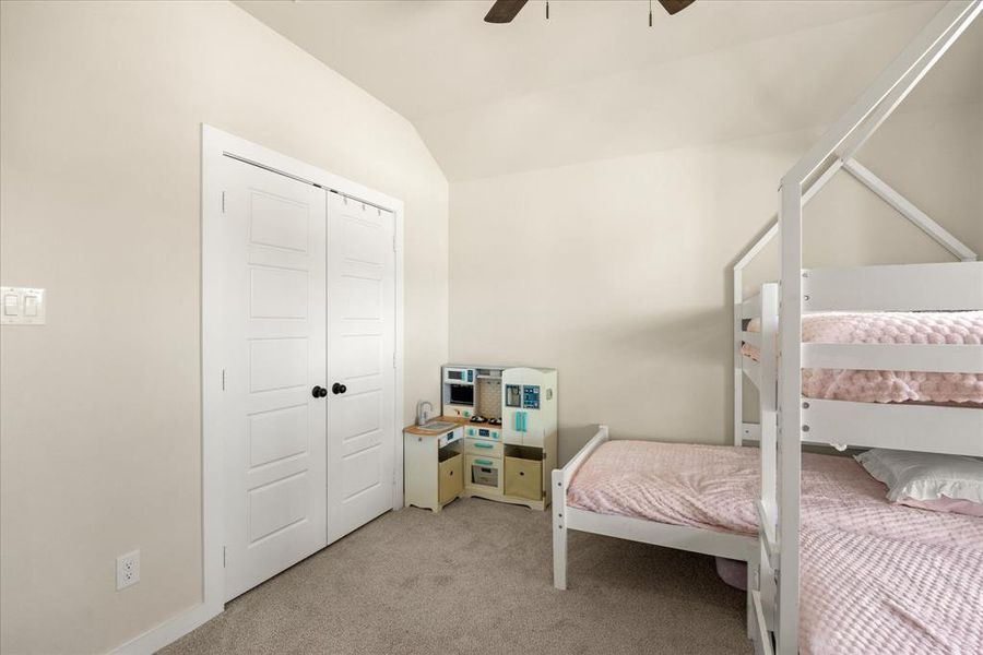 Bedroom with lofted ceiling, light colored carpet, a closet, and ceiling fan