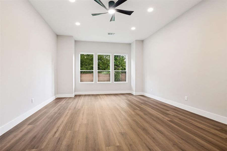 Spacious room featuring wood-finish flooring, white baseboards, and neutral wall tones