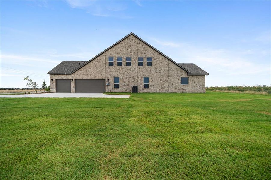 View of side of home featuring brick siding, a yard, driveway, and an attached garage View of side of home featuring brick siding, a yard, driveway, and an attached garage