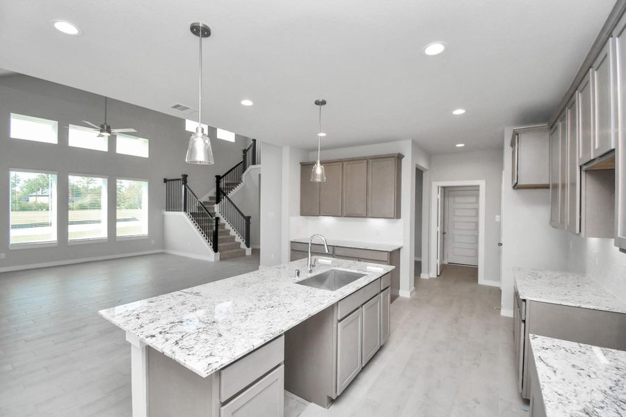 The kitchen is a culinary haven, featuring granite countertops, a tile backsplash, stainless steel appliances, 42” upper cabinets, and undercabinet lighting. Sample photo of completed home with similar floor plan. Actual colors and selections may vary. The kitchen is a culinary haven, featuring granite countertops, a tile backsplash, stainless steel appliances, 42” upper cabinets, and undercabinet lighting. Sample photo of completed home with similar floor plan. Actual colors and selections may vary.