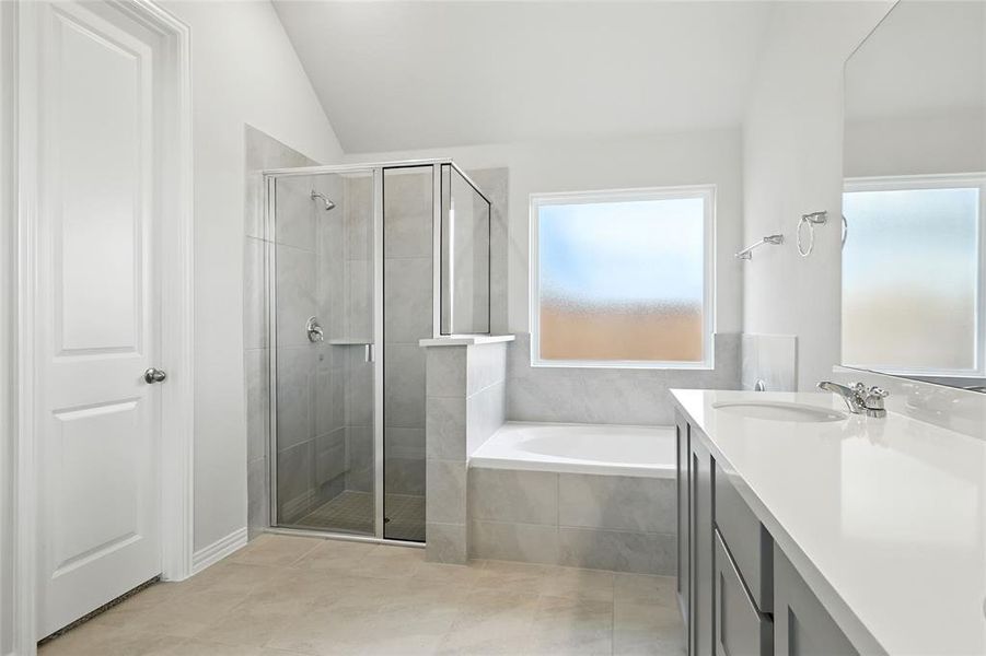 Bathroom featuring a garden tub, vanity, a shower stall, vaulted ceiling, and light tile patterned floors Bathroom featuring a garden tub, vanity, a shower stall, vaulted ceiling, and light tile patterned floors
