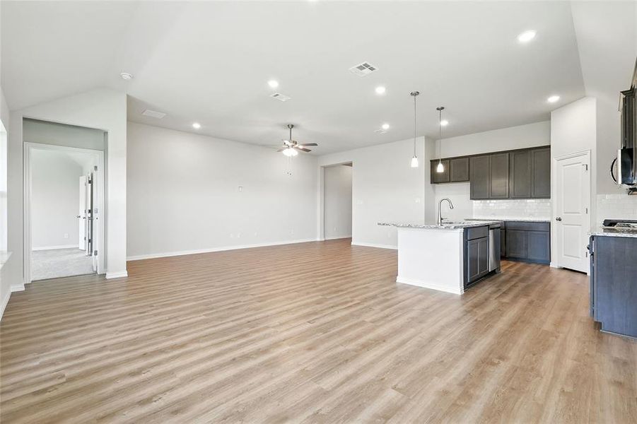 Kitchen featuring open floor plan, a kitchen island with sink, recessed lighting, light wood-style floors, and backsplash
