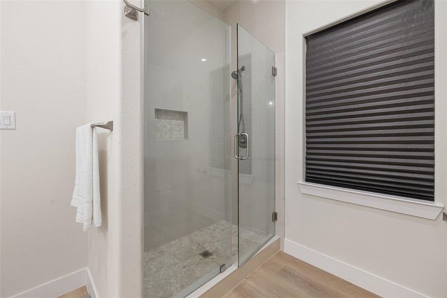 Bathroom including a walk-in shower with shower door and tile