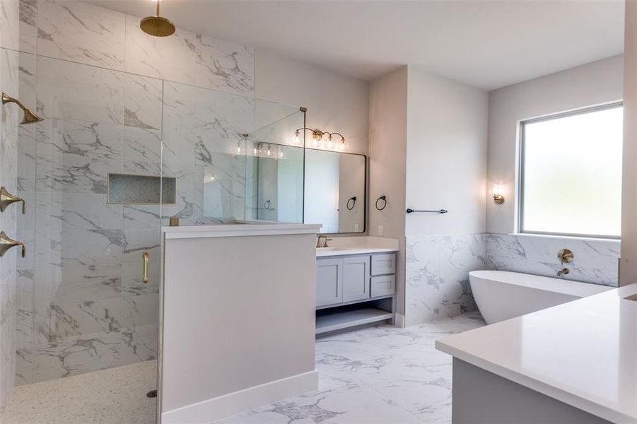 Full bath featuring tile walls, a marble finish shower, a freestanding bath, vanity, and a wainscoted wall Full bath featuring tile walls, a marble finish shower, a freestanding bath, vanity, and a wainscoted wall