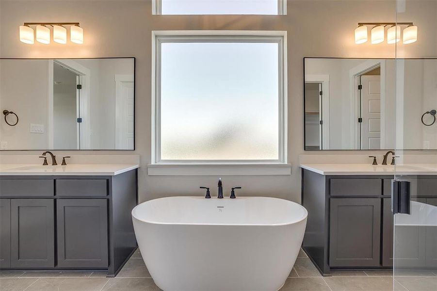 Bathroom featuring a freestanding bath, two vanities, a sink, and tile patterned flooring Bathroom featuring a freestanding bath, two vanities, a sink, and tile patterned flooring