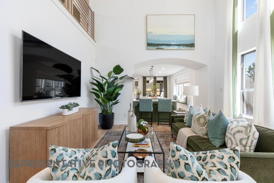 Living area featuring arched walkways, a towering ceiling, and wood finished floors Living area featuring arched walkways, a towering ceiling, and wood finished floors