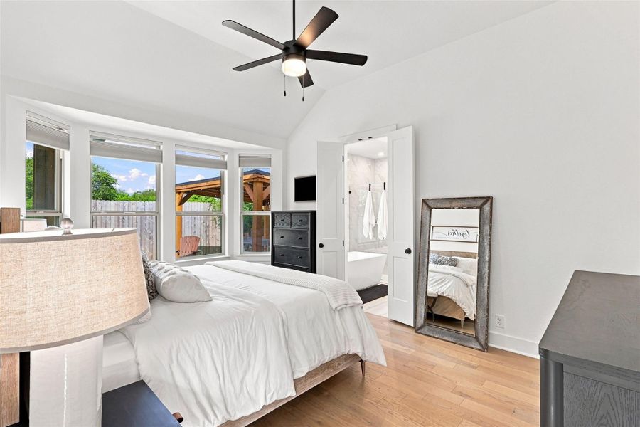 High vaulted ceilings and rich wood floors anchor this serene primary bedroom retreat.