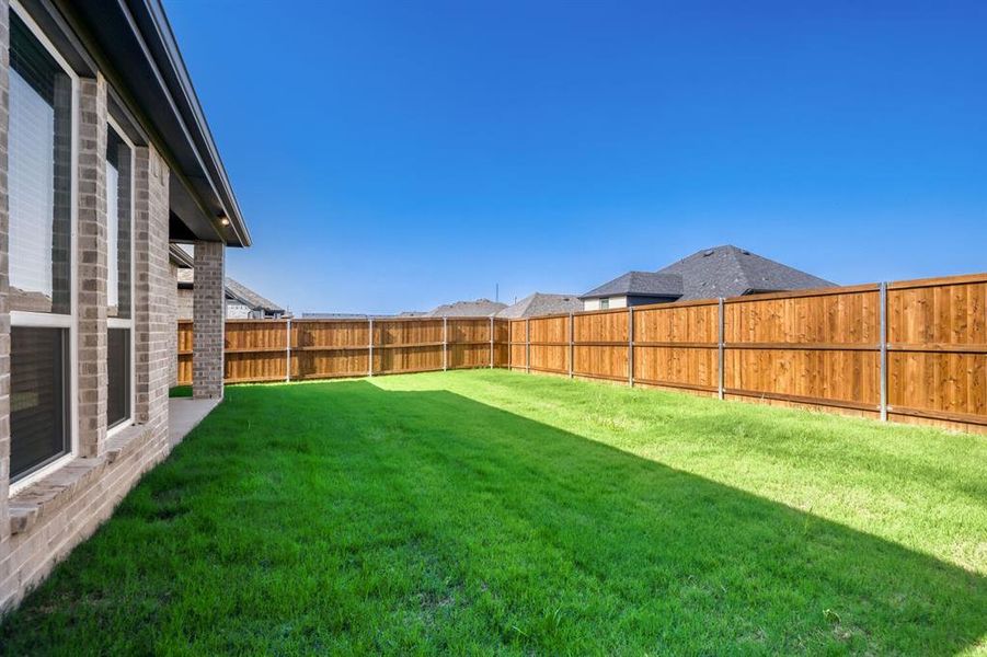 Expansive backyard featuring a manicured lawn and a wooden privacy fence