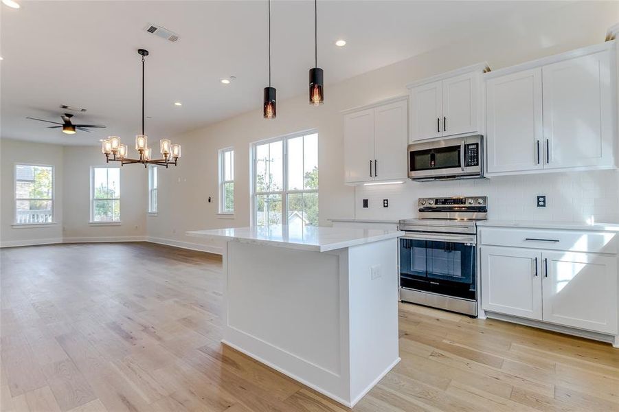 Kitchen featuring white cabinetry, a center island, stainless steel appliances, and light hardwood / wood-style flooring