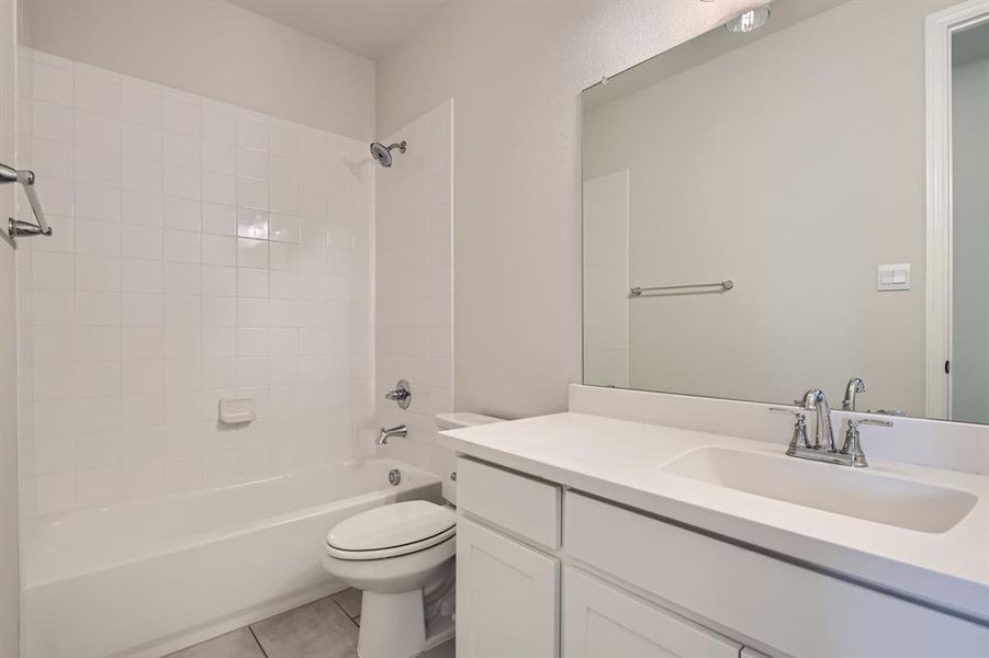 Full bathroom with vanity, tiled shower / bath combo, toilet, and tile patterned floors