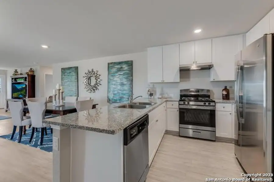 Kitchen featuring stainless steel appliances, a peninsula, light stone countertops, recessed lighting, and light wood-style floors Kitchen featuring stainless steel appliances, a peninsula, light stone countertops, recessed lighting, and light wood-style floors