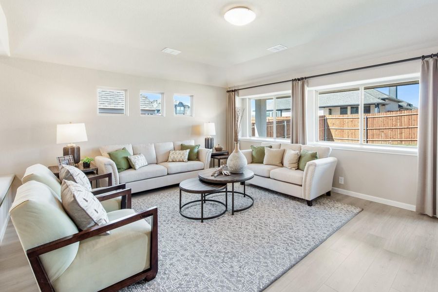 Bright living room with cream sofas, round coffee table, and large windows overlooking a backyard fence Bright living room with cream sofas, round coffee table, and large windows overlooking a backyard fence
