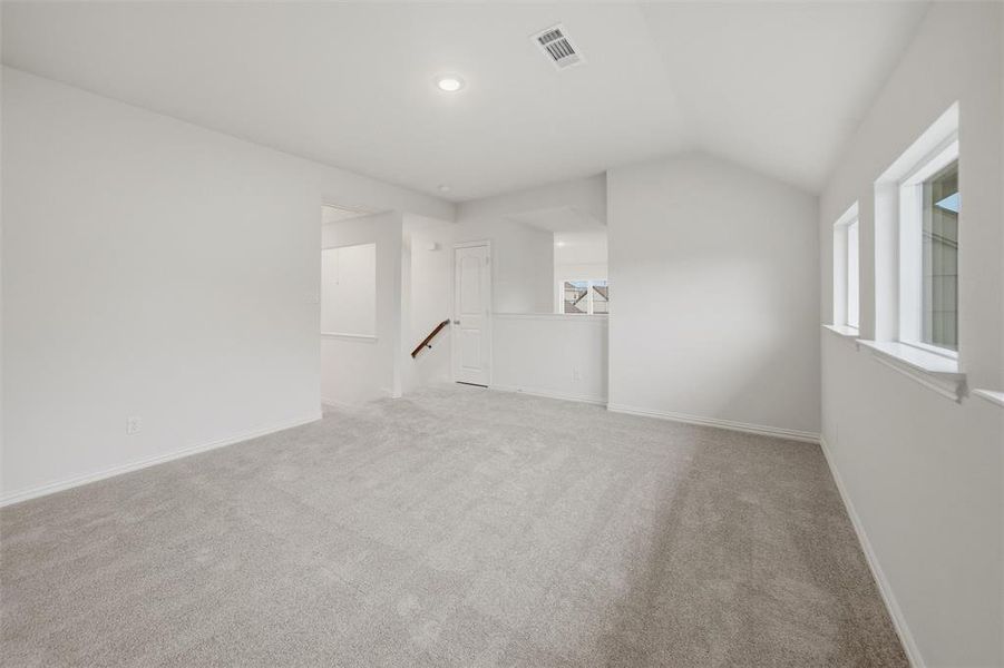 Empty room with light colored carpet and lofted ceiling