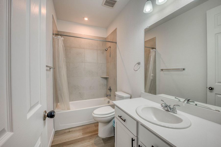 Clean lines and stone tile highlights create an inviting bathroom space with wood-look flooring.