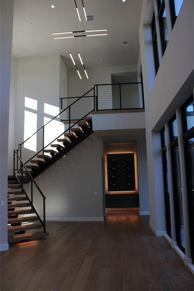 Staircase with wood-type flooring and a high ceiling