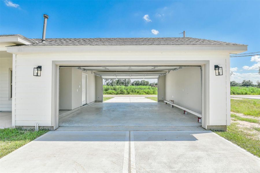 Double garage doors open to a spacious interior and extend to an oversized paved driveway, perfect for parking extra vehicles, a boat, or creating a versatile work or hobby area.