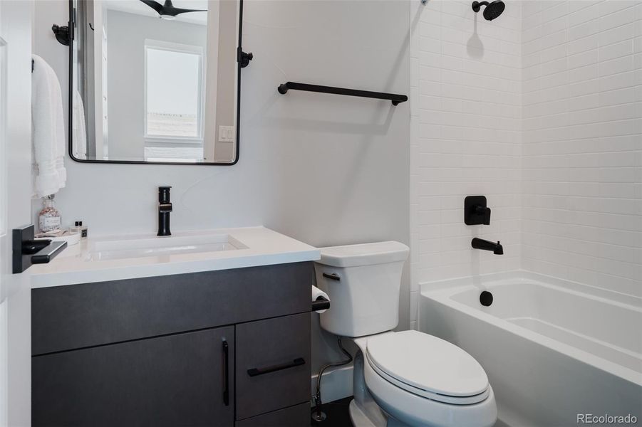 The ensuite bathroom is elegantly finished with crisp white subway tiles and contrasting hexagonal black floor tiles.